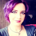 A woman with purple hair, representing The Plural Association, is posing for a picture to raise awareness about OSDD and promote the Power to the Plurals.